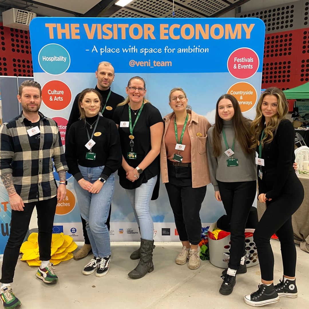 People standing in front of a sign that says 'The Visitor Economy'